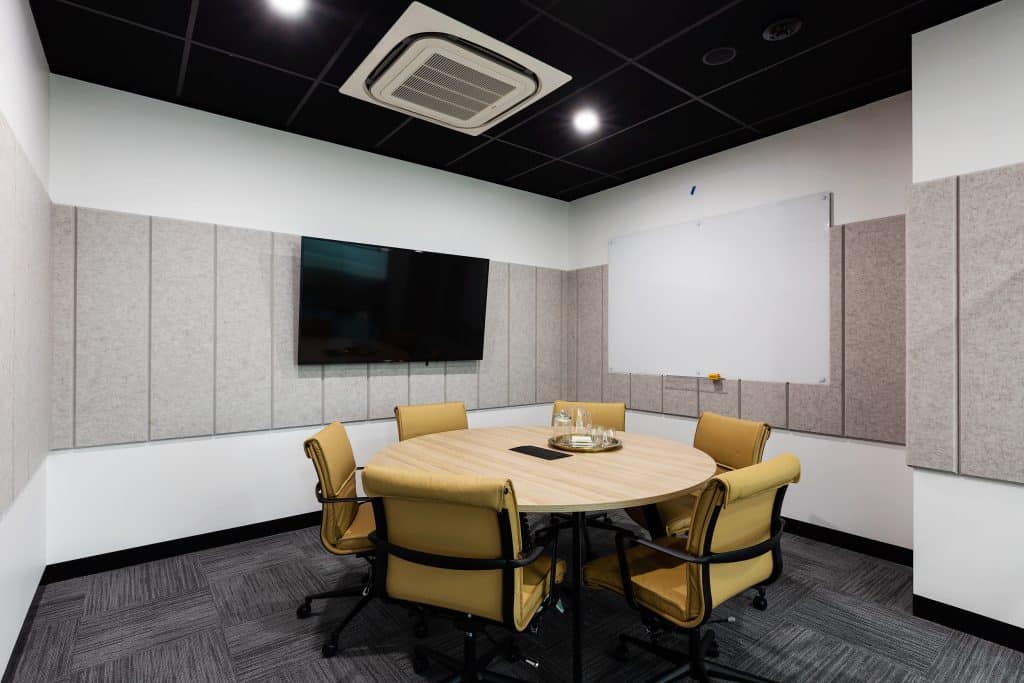 a rounded table meeting room for six people with tv and whiteboard
