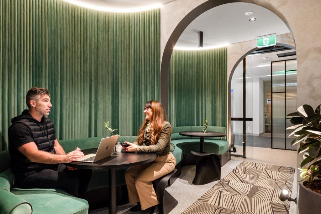 two people having a meeting in the black table and green sofa coworking space