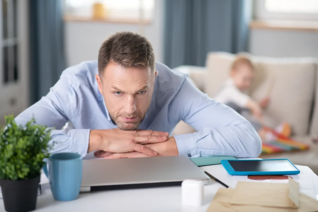 Home worker with baby pondering the benefits of working in an office vs home
